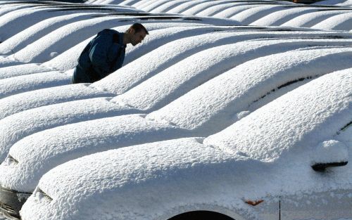 MÃœNCHEN - Bij deze Ford-dealer liggen er over de auto’s een witte deken. In het zuiden van Duitsland viel donderdag op vrijdag een flink pak sneeuw. - Foto EPA