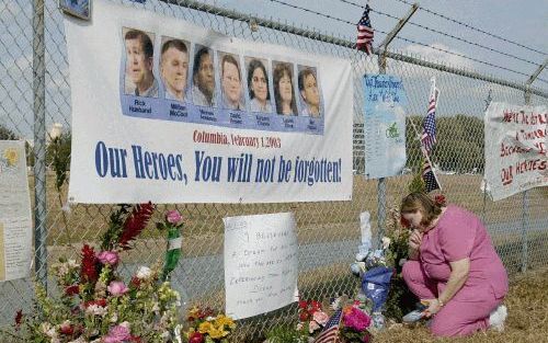 HOUSTON - Sabrina Johnson (rechts) knielt neer bij een van de vele plaatsen rondom het Houston Ruimtecentrum in Houston (Texas) waar duizenden mensen boodschappen, briefjes, bloemen en ballonnen neerleggen ter nagedachtenis aan de zeven omgekomen astronau