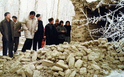 BACHU - Een groepje Chinezen neemt de schade op die een krachtige aardbeving gisteren in de provincie Xinjiang aanrichtte. Bij het natuurgeweld kwamen meer dan 300 mensen om het leven en werden ruim 9000 huizen verwoest. - Foto EPA