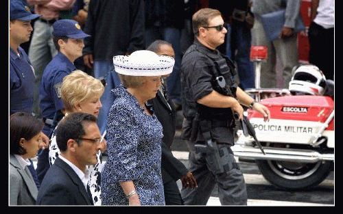 SAO PAULO - Onder het geroep van demonstranten bekijkt koningin Beatrix in Sao Paulo restauratieprojecten in de binnenstad. Rechts van haar een zwaarbewapende agent, links de burgemeester van Sao Paulo, Marta Suplicy. - Foto RD, Henk Visscher