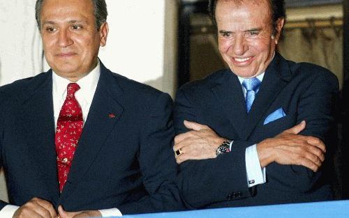 BUENOS AIRES - De Argentijnse presidentskandidaat Carlos Saul Menem (r.) verscheen vanmorgen met zijn running mate Juan Carlos Romero in Buenos Aires op een balkon waar hij werd toegejuicht door aanhangers. Menem mag door naar de tweede en beslissende ste