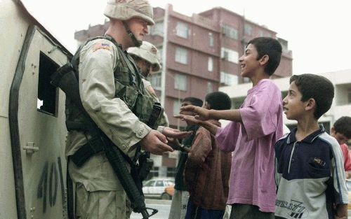 BAGDAD - Een Amerikaanse soldaat speelt met een groepje Palestijnse kinderen in Bagdad. Na de verdrijving van Saddam Hussein krijgen de Palestijnen in toenemende mate met haatgevoelens van de Iraakse bevolking te maken. - Foto EPA