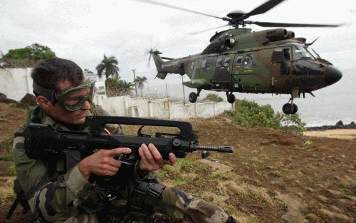 MONROVIA - Een Franse militair houdt rebellen in de Liberiaanse hoofdstad Monrovia op een afstand als een helikopter met buitenlanders opstijgt. - Foto EPA