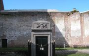 SOMMELSDIJK â€“ De ingang van de grafkelder van de adellijke familie Van Aerssen achter de hervormde kerk in Sommelsdijk. Bij een felle kerkbrand in het bedehuis in 1799 kwam de ingang van het familiegraf los van de kerk te staan. Rechts op de achtergrond