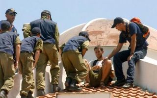 GADID - IsraÃ«lische soldaten proberen een joodse kolonist van het dak van een huis te halen. Foto EPA