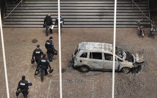 Een arrestatieteam gaat het stadhuis van Almelo binnen. Voor het stadhuis de door de gijzelnemer in brand gestoken auto. Foto's ANP