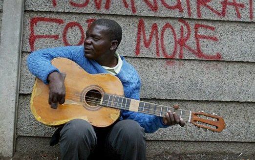 Een muzikant in Zimbabwe voor een afrastering met de tekst: Vote Tsvangirai. Foto EPA