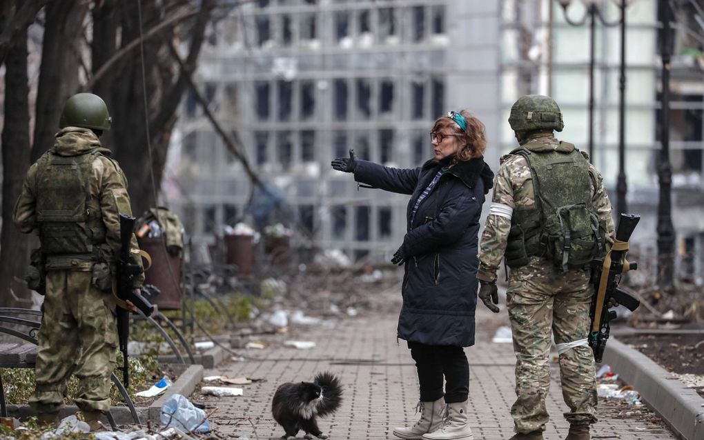 Russische militairen in gesprek met een bewoner van de zwaar verwoeste stad Marioepol. beeld EPA, Sergei Ilnitsky