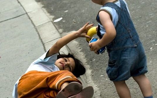 Een jongen geeft een jonge zwerfster een banaan in Skopje, Macedonië. Foto EPA