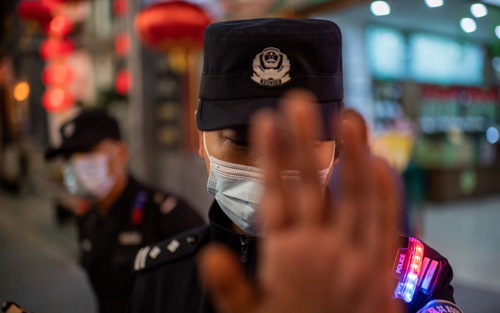 Een Chinese politieagent probeert een fotograaf te stoppen. beeld AFP, Nicolas Asfouri