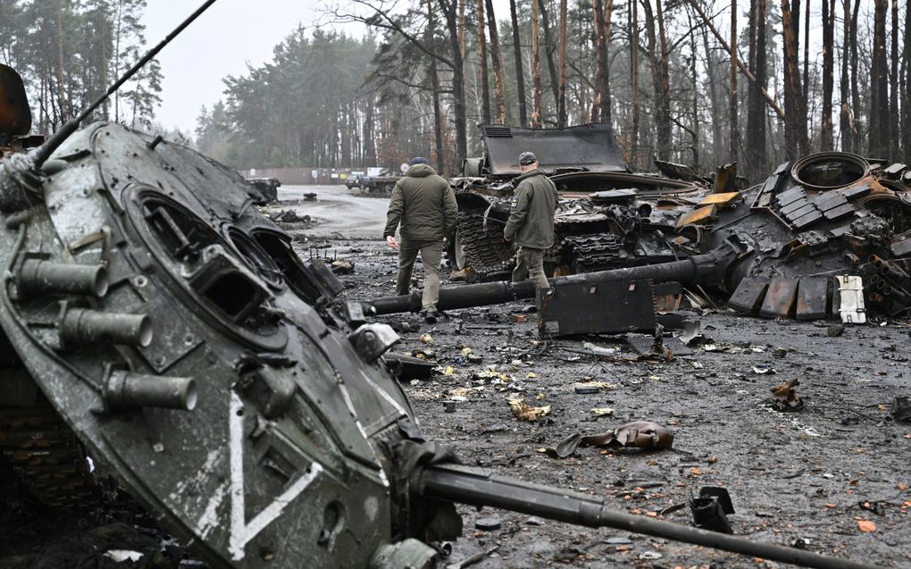 Oekraïense militairen lopen voorbij een vernietigde Russische tank en pantserinfanterievoertuig in een dorp ten westen van Kiev. beeld AFP, Genya Savilov