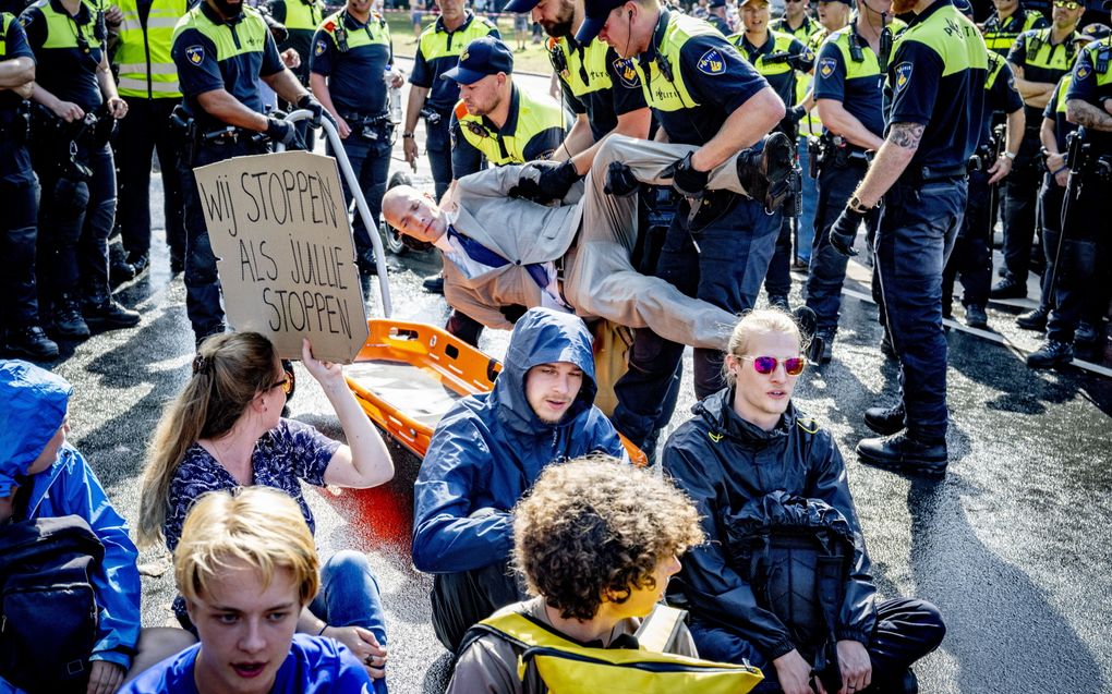 Klimaatactivisten demonstreren zittend op het wegdek van de A12 en worden afgevoerd door de politie. beeld ANP, Robin Utrecht