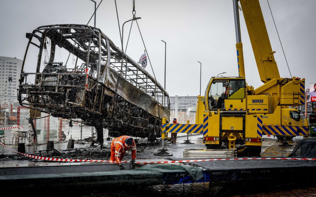 Een uitgebrande bus bij zalencentrum Opera in Den Haag wordt weggetakeld. Twee groepen Eritreeërs kregen het zaterdag in de hofstad met elkaar aan de stok met veel schade tot gevolg.  beeld ANP, Robin Utrecht