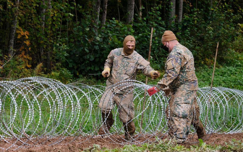 Soldaten construeren een prikkeldraadversperring op de grens tussen Letland en Wit-Rusland. beeld EPA, Valda Kalnina