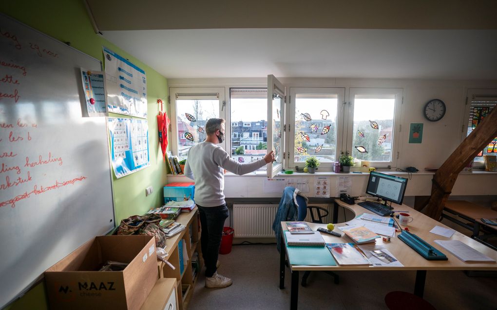 Een leerkracht van een basisschool opent een raam in een klaslokaal voor extra ventilatie. beeld ANP, Jeroen Jumelet