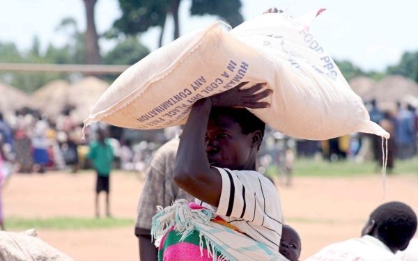 Een Ugandese vrouw draagt een zak voedsel van het VN-Wereldvoedselprogramma (WFP) naar haar onderkomen. Het WFP verspreidt wereldwijd vele tonnen graan. Foto EPA