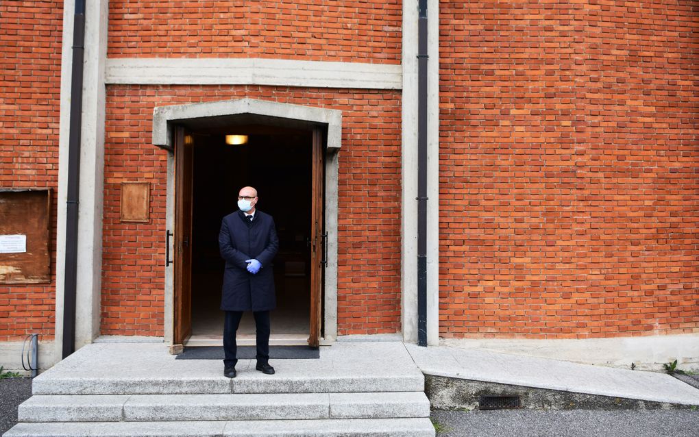 Een kistdrager staat voor een kerk in Bergamo. beeld AFP, Piero Cruciatti