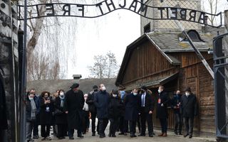 De Franse premier Jean Castex (midden) staat bij de poort tijdens een bezoek aan voormalig Duits concentratie- en vernietigingskamp Auschwitz-Birkenau in Oswiecim, Polen. beeld AFP, Bartosz Siedlik