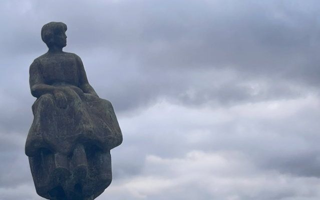 Schrijfster Anita Kramer-Post bij het vissersmonument van Urk: platen vol namen, bij het beeld van een vrouw die uitkijkt over zee. beeld Hendrik Kramer