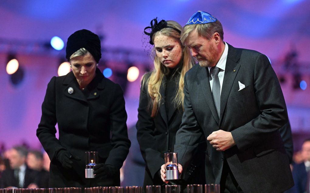 Koningin Maxima, prinses Amalia en koning Willem-Alexander plaatsen kaarsen voor de treinwagon.beeld AFP, Sergei Gapon 