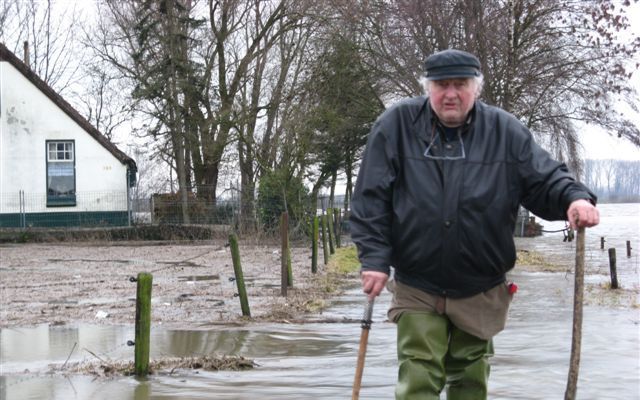 Aan de Waalbandijk bij Dodewaard worstelt de 80-jarige Jan van Hensbergen door het water rond zijn dijkwoning. Foto RD