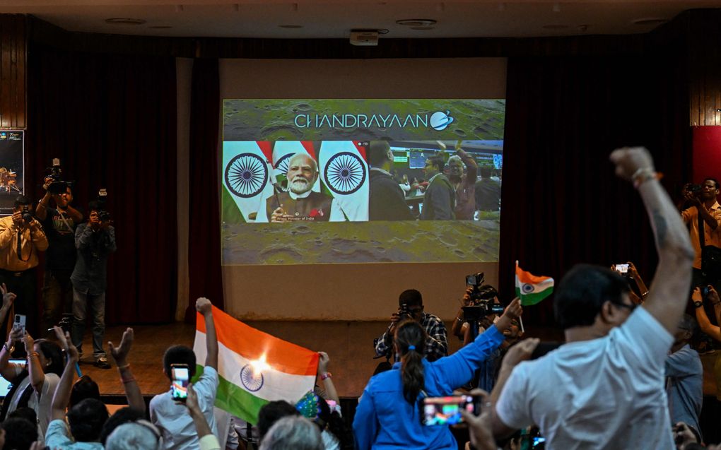 Mensen zwaaien met de vlag van India terwijl de Indiase premier Narendra Modi (m., scherm) de Indian Space Research Organisation (ISRO) feliciteert met de succesvolle maanlanding van het Chandrayaan-3 ruimtevaartuig op de zuidpool van de maan. beeld AFP, Punit PARANJPE