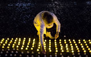 Rijen waxinelichtjes worden geplaatst door vrouwen op het Plein tijdens het uur van licht. 