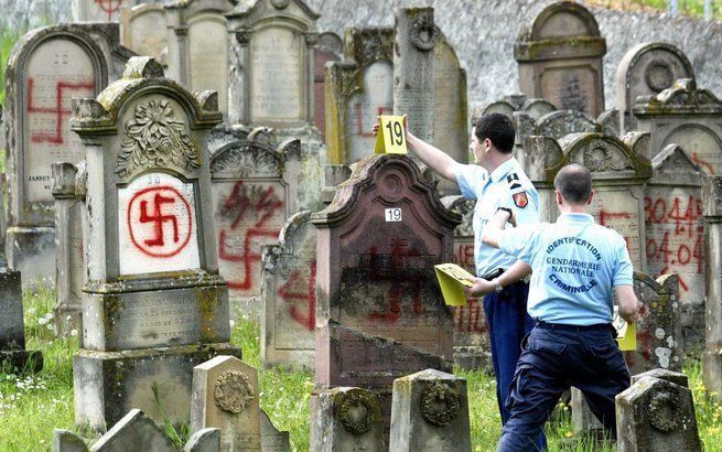 Agenten nemen 30 april 2004 de schade op die is aangericht op de Joodse begraafplaats in Herrlisheim in het oosten van Frankrijk. Foto EPA