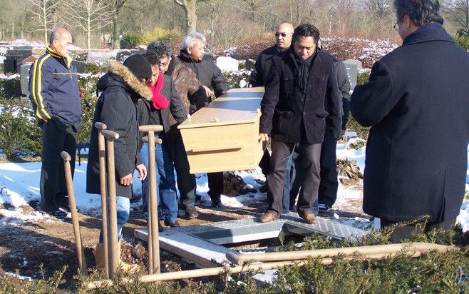 De begrafenisplechtigheid in Molukse kring gaat gepaard met tal van rituelen. Het graf wordt door de familie dichtgegooid, nadat bloemblaadjes en veel parfum in het gat zijn beland. Foto Jacob Hoekman