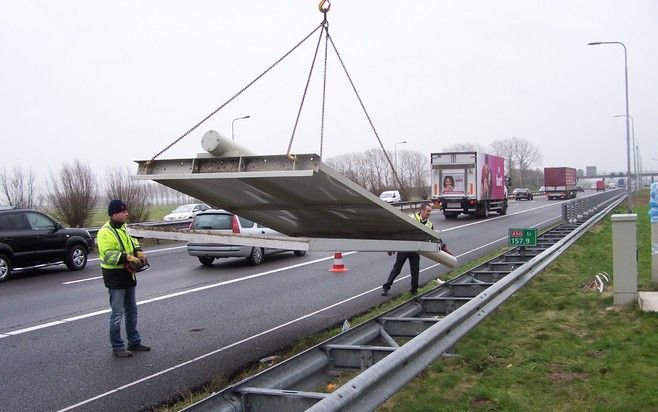 VALBURG - Gerard van Denter (links) en Piet van Sandijk transporteren een door de storm afgebroken verkeerspaal naar de kraanwagen.