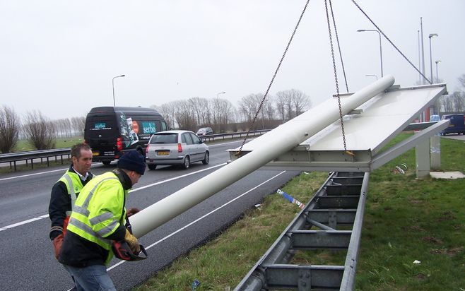 VALBURG – De westerstorm die gisteren over Nederland trok, veroorzaakte vooral verkeersproblemen. Een verkeerspaal bij Valburg waaide om en werd met vereende krachten in veiligheid gebracht. - Foto ANP