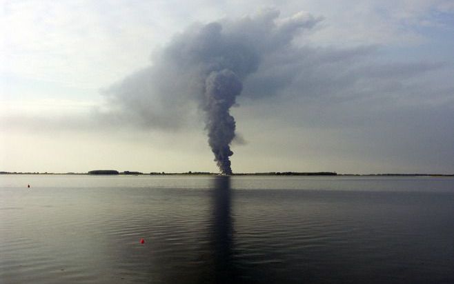 Aan de overkant van de Oosterschelde zien toeschouwers een enorme rookkolom boven Tholen hangen. Foto Gerard Maas