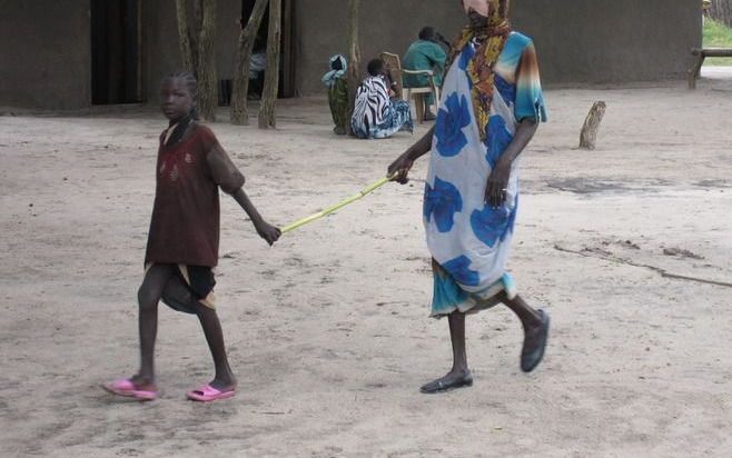 LANKIEN – Het hoge percentage blinden in Zuid-Sudan komt mede door de vele burgeroorlogen in het gebied. Foto: een Sudanese vrouw wordt door haar dochter naar de kliniek gebracht.Foto Nico Buisman