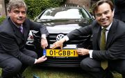 DRIEBERGEN - Minister Eurlings (r) reikt maandag in Driebergen het eerste nieuwe nummerbord uit aan de eigenaar. Foto ANP