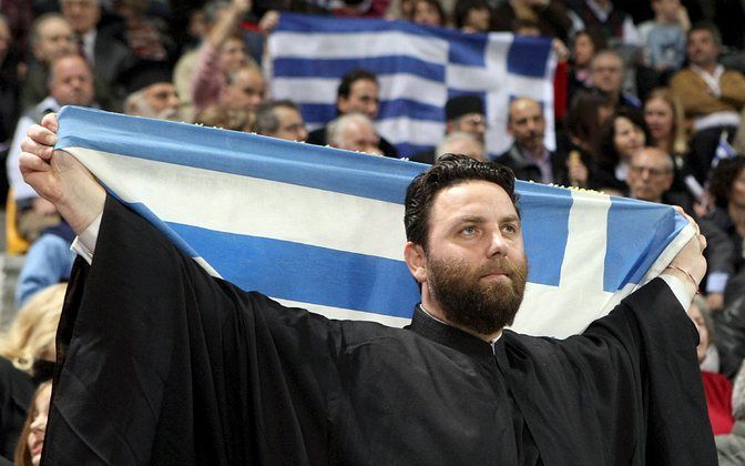 Een Grieks orthodoxe priester protesteert tijdens een bijeenkomst in een basketbalhal in het Noord Griekse Tessaloniki, eerder deze maand, tegen het gebruik van de naam Macedonië door het gelijknamige buurland. Foto EPA