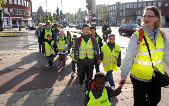 DEN HAAG – Kinderen van de Ds. D. J. Karresschool in Den Haag steken de Zuiderparklaan over. Ze vormen een ”loopbus”: onder begeleiding lopen zij een vaste route door de wijk naar school. „Ik vind het leuk om met de loopbus te gaan”, zegt Freddie de Jong,