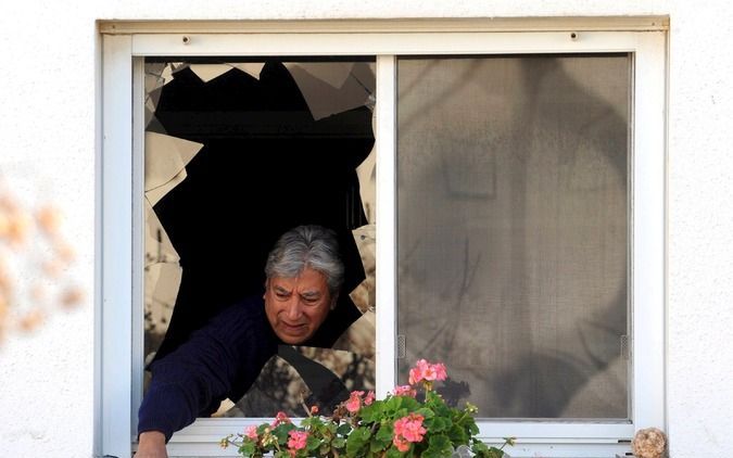 Een Israelische vrouw neemt de schade op die een Palestijnse Katyusharaket tijdens de Gaza-oorlog heeft aangericht. Foto EPA