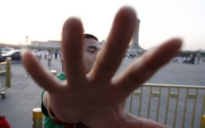 Een politieman houdt journalisten op afstand bij het Plein van de Hemelse Vrede in Peking. Foto EPA