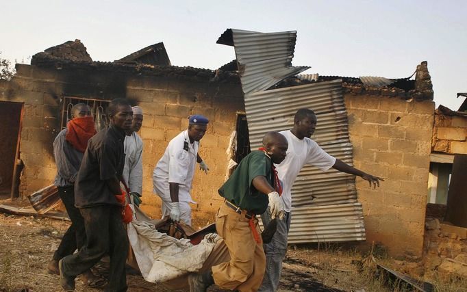 Sinds 2001 zijn er in en rond Jos zeker 2000 doden gevallen bij geweld tussen moslims en christenen. Foto: Nigeriaanse mannen dragen een slachtoffer van religieus geweld in het dorp Kuru Jantar weg, 22 januari 2010. In januari kwamen in de regio Plateau S