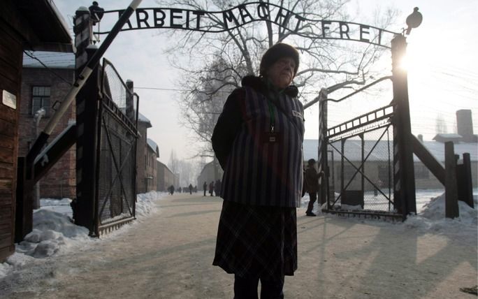 Een voormalig gevangene onder de poort van Auschwitz. Boven de poort staat de bekende leus ”Arbeit macht frei". Woensdag begon de herdenking van de vijfenzestigste bevrijdingsdag van het concentratiekamp. Foto EPA.