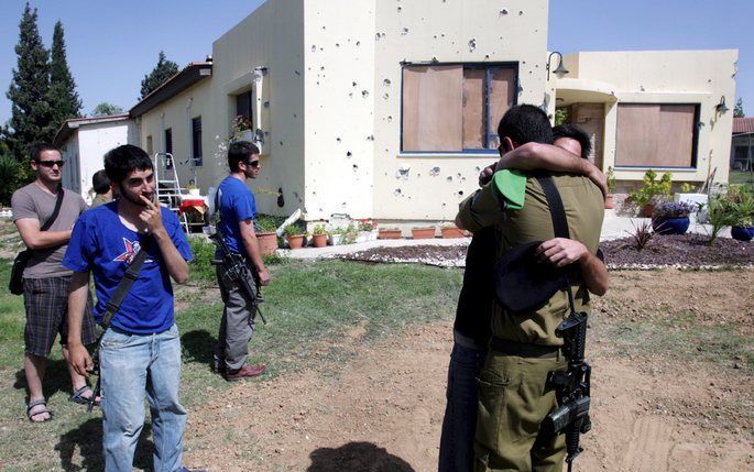 De zoon van Ades’ buurman omarmt kameraden uit het leger, nadat zijn vader bij een Palestijnse raketaanval om het leven is gekomen. Op de achtergrond het beschadigde huis, waar het projectiel op enkele meters afstand terechtkwam. Foto EPA