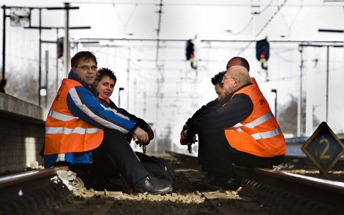 ALMERE - Ruim vijftig conducteurs en machinisten zitten vrijdag midden op het spoor van Almere Centraal. Gekleed in oranje hesjes leggen ze reizigers uit dat de treinen toch echt een uur lang niet rijden. Foto ANP