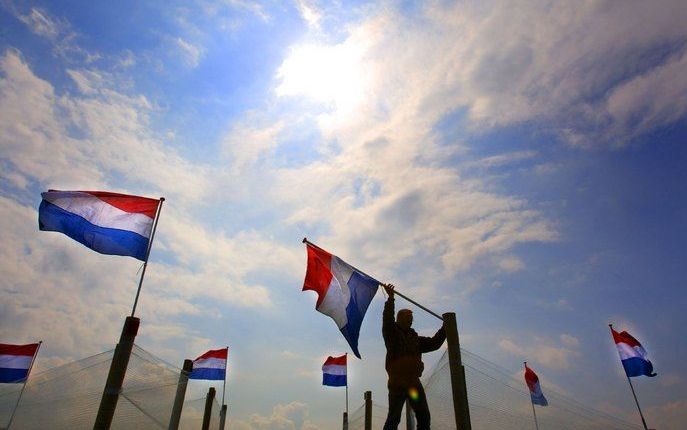 MAKKUM – De vlag in top op Koninginnedag. Een boer was dinsdag bezig de Hollandse driekleur op diverse plekken op zijn land te plaatsen. Woensdag bezoeken koningin Beatrix en leden van de koninklijke familie Makkum en Franeker. Foto ANP