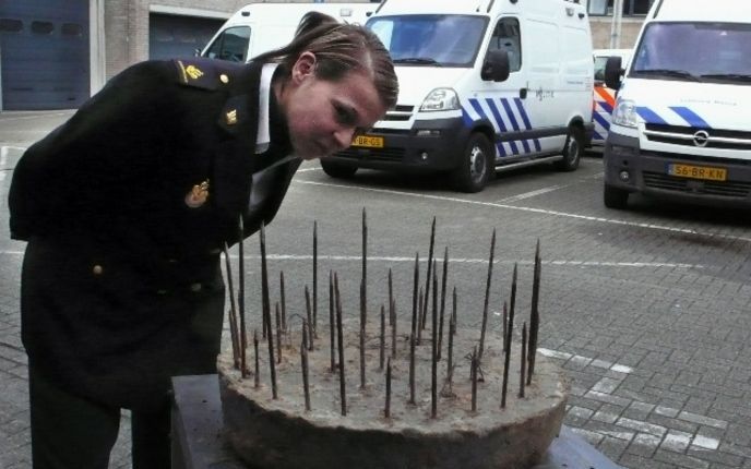 HELDEN - Een politieagente bekijkt een boobytrap met ijzeren pinnen die verborgen zat in een valkuil in de bossen van het Limburgse Helden. Foto: ANP