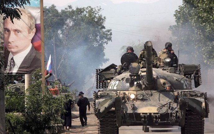 Een Russische tank passeert in de Zuid-Ossetische hoofdstad Tschinvali een poster van de Russische premier en oud-president Vladimir Poetin. Foto EPA