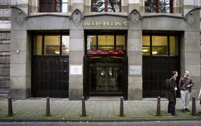 AMSTERDAM - Mensen staan te praten terwijl de koers van de AEX op de lichtkrant buiten het beursgebouw langskomt op het Beursplein in Amsterdam. Foto ANP