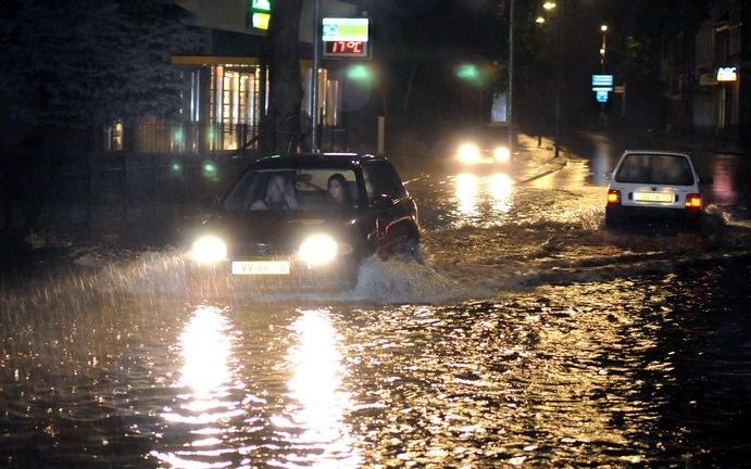 Een auto rijdt zaterdagavond door Assen, waar diverse straten blank stonden als gevolg van zware regenval. Een groot deel van de provincie Drenthe is zaterdagavond getroffen door noodweer. Foto ANP