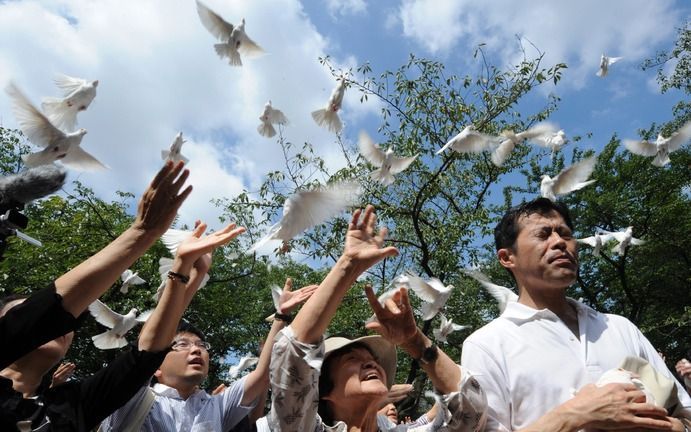 TOKIO - Ook in Japan wordt zaterdag het einde van de Tweede Wereldoorlog herdacht. Bij een tempel in Tokio laten Japanners vredesduiven op. Foto EPA