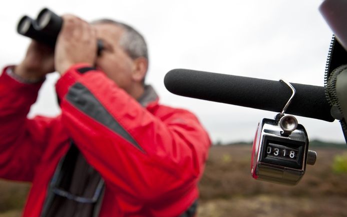 LAREN - Een klikapparaat om de tel bij te houden. Leden van de Natuur- en Vogelwacht Dordrecht tellen zaterdag trekvogels op de Zuiderheide bij Laren. Foto ANP