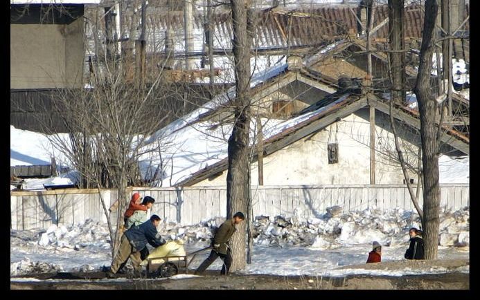 Noord-Koreanen hebben nauwelijks nog brandstof en moeten zelf hun vracht trekken. Foto: sjouwen burgers met een kar, in een gebied dat grenst aan China. Foto RD, Henk Visscher